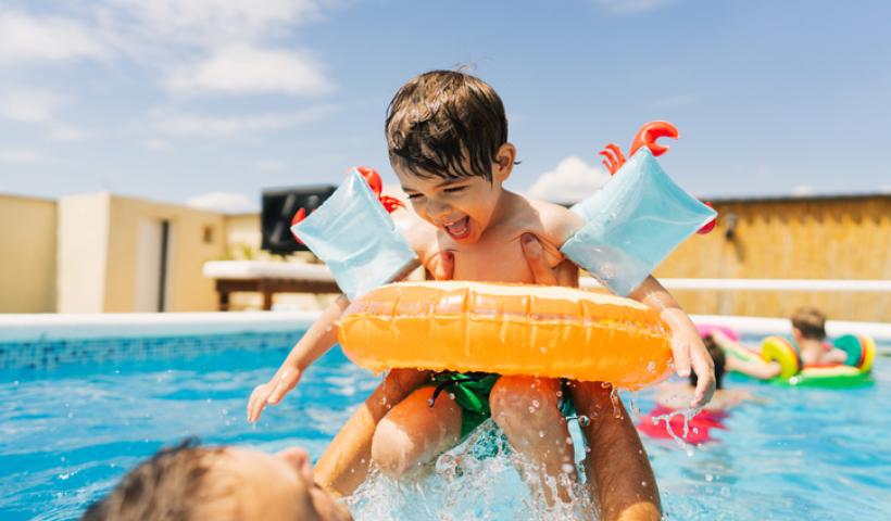 Child playing in pool with parents