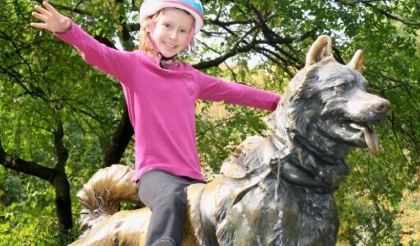 child sitting on top of dog statue