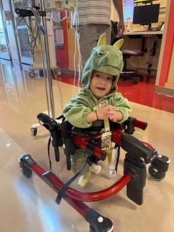 Toddler in dinosaur costume, using a walker