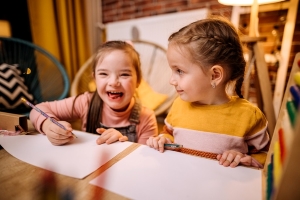 Two young girls drawing at table