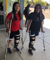 Twin teen girls on crutches
