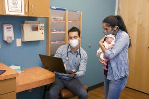 Masked provider and mother with newborn in exam room