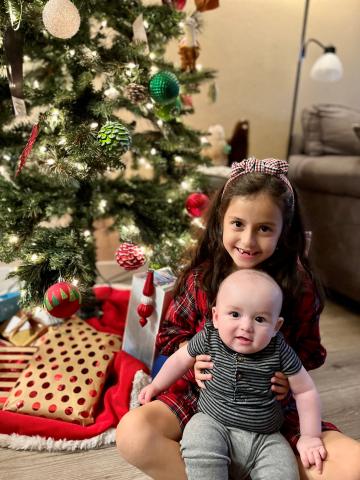 Older girl and baby brother next to Christmas tree