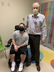 Masked provider standing next to patient in wheelchair