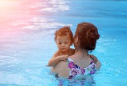 Mother holding infant in pool