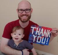 Father and toddler holding Thank You sign
