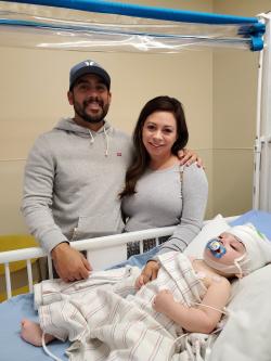 Mother and father stand next to baby in hospital crib