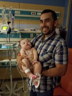Father holding baby in hospital room