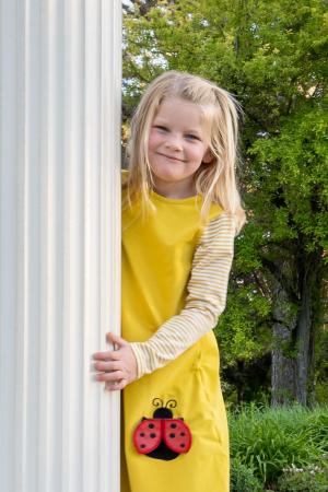 Young girl in yellow dress with ladybug on it