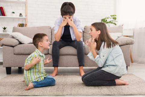 Children arguing in front of mom on couch