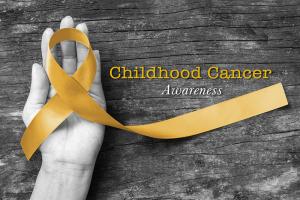 Hand holding gold ribbon representing Childhood Cancer