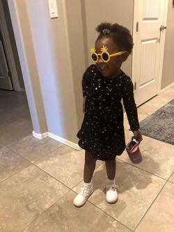 Toddler in black dress and yellow sunglasses