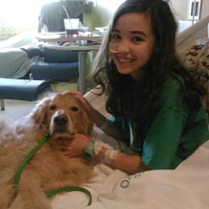 Young girl in hospital bed with therapy dog