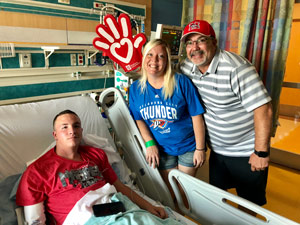 Teen patient in hospital bed with parents standing nearby