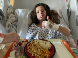 Girl in hospital bed giving thumbs up