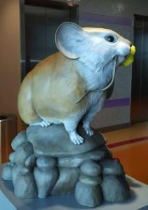 Statue of a pika, with yellow flower in mouth