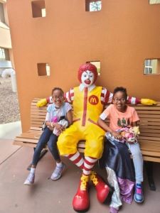 Twin girls on bench with Ronald McDonald statue