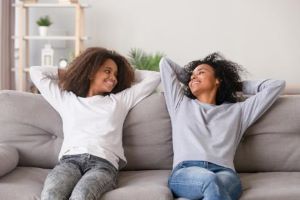 Mother and teen daughter relaxing on couch
