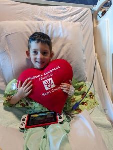 Young boy holding a large heart pillow to his chest