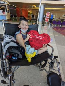 Smiling boy in wheelchair holding large heart pillow