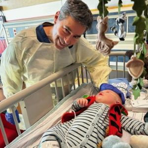 Infant in hospital crib with doctor standing over