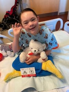 Boy in hospital bed, holding stuffed teddy bear