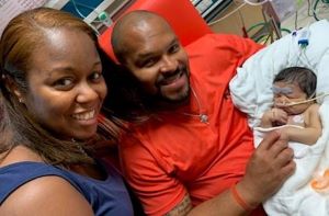 Mother and father holding infant in NICU