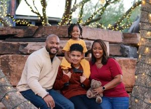 Family of 4 posing between trees