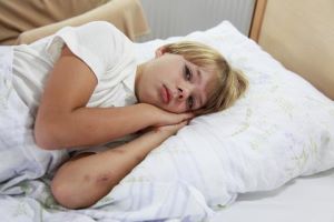 Sick child in bed with bruises on arms