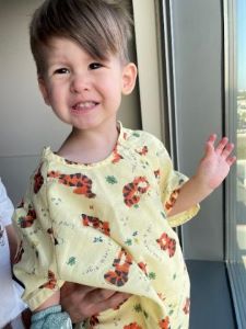 Smiling toddler in yellow hospital gown