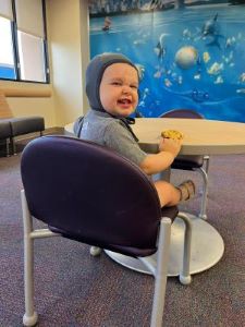 Smiling toddler sitting in chair, looking back