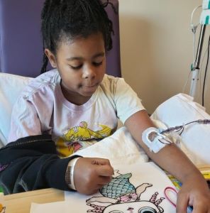 Girl coloring in hospital bed