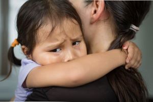 Crying child hugging caregiver