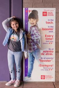 Child standing next to height measuring poster