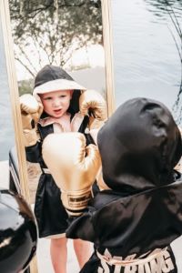 Boy in boxing robe and gloves, looking in mirror
