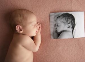 Sleeping infant posing with photo of twin