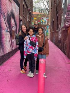 Family of 4 posing in a pink alleyway