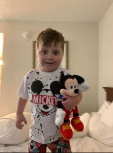 Toddler in Mickey Mouse shirt, smiling at camera