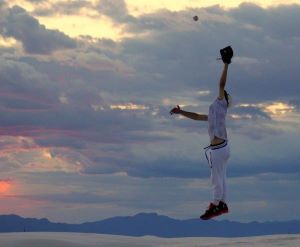 Teen baseball player jumping to catch a ball