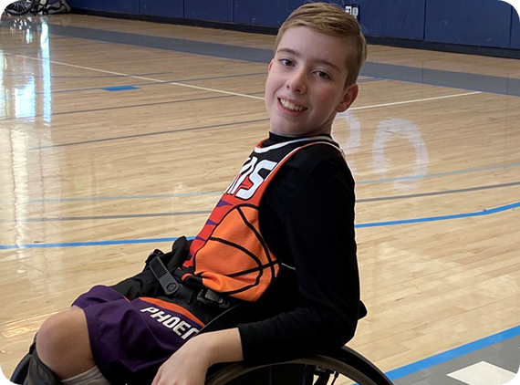 Teen boy in wheelchair smiling on basketball court