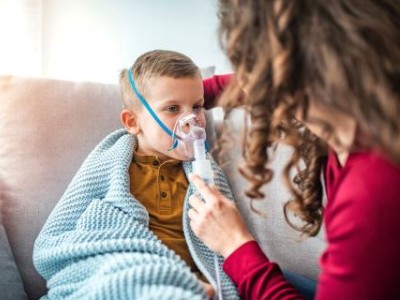 Child in blanket wearing a breathing treatment mask