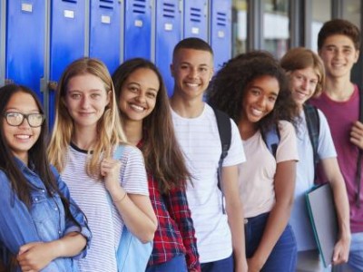 Group of smiling teens standing in front of lockers