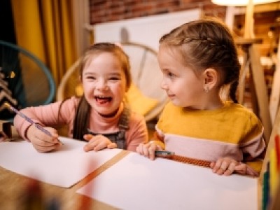 Two young girls drawing at table