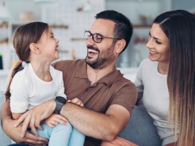 Mother, father and child sitting on couch, laughing