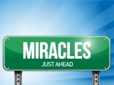 Street sign that reads Miracles Just Ahead