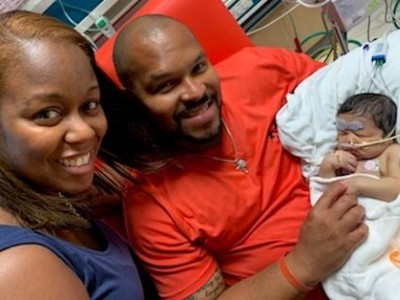 Mother and father holding infant in NICU