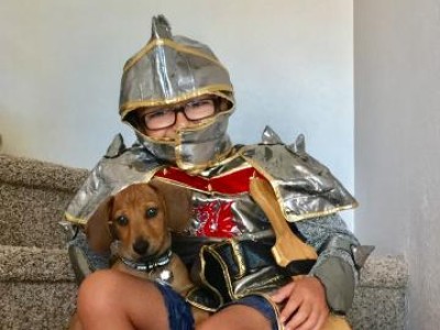 Boy dressed as a knight, sitting on stairs with small dog
