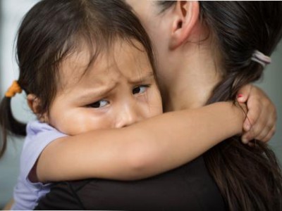 Crying child hugging caregiver