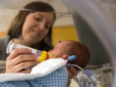 Mother feeding infant in incubator