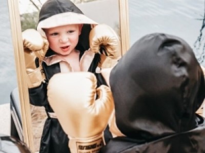 Boy in boxing robe and gloves, looking in mirror